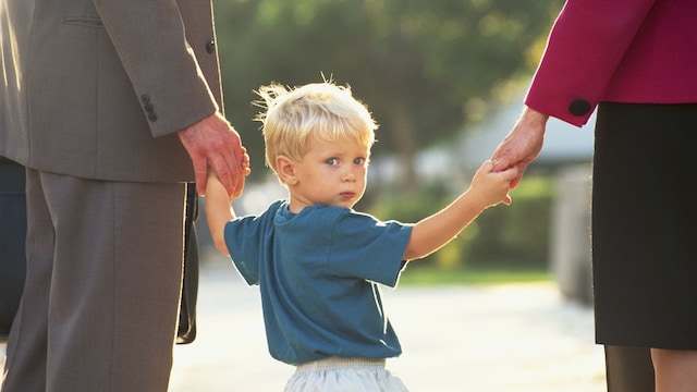 Niño paseando de la mano con sus padres