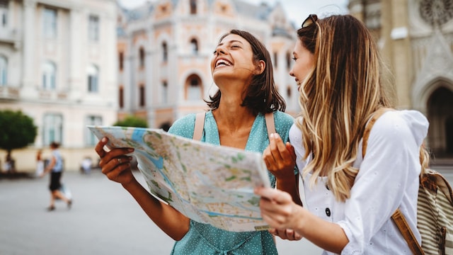 dos amigas sonrientes haciendo turismo en vacaciones, con un mapa en la mano