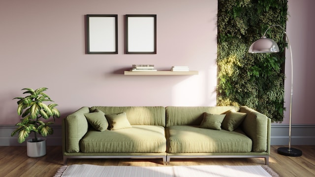 Salón de una casa moderna con las paredes en malva, sofá en verde y un jardín vertical en la parte derecha. Delante, una lámpara de pie y, al otro lado del sofá, una planta en el suelo. Cuadros, un estante y una alfombra en el suelo.