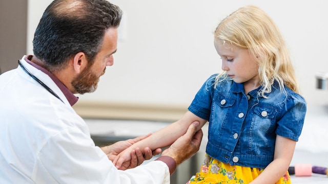 Pediatra revisa el brazo lastimado de una niña