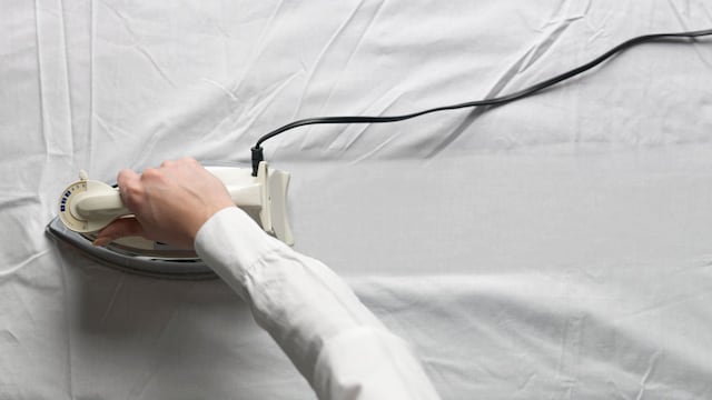 Mujer planchando una tela blanca con una plancha a vapor
