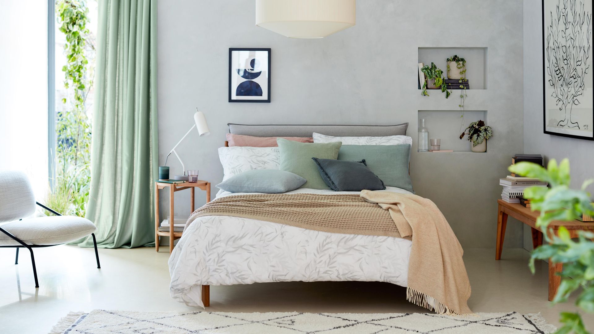 Dormitorio con paredes grises, hornacinas, lámpara de techo, cuadros, cortinas, cabecero tapizado, plantas y alfombra