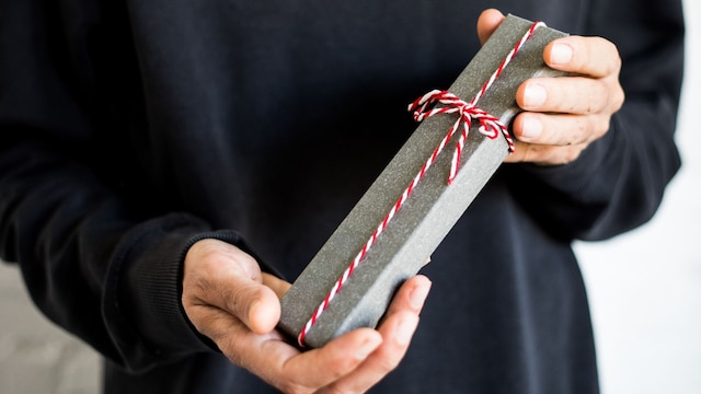 Hombre sujetando en un plano detalle de sus manos un regalo por San Valentin