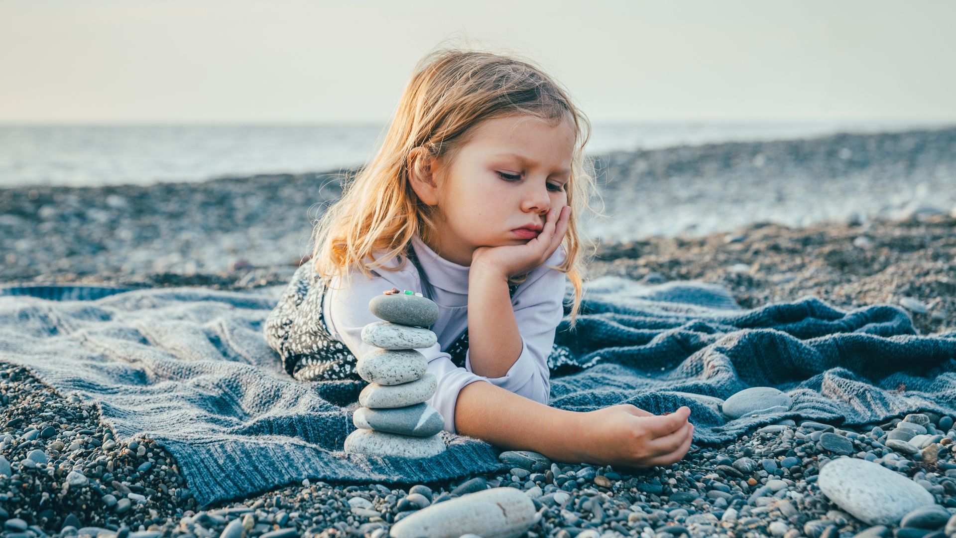 Niña aburrida en verano, tumbada en la playa
