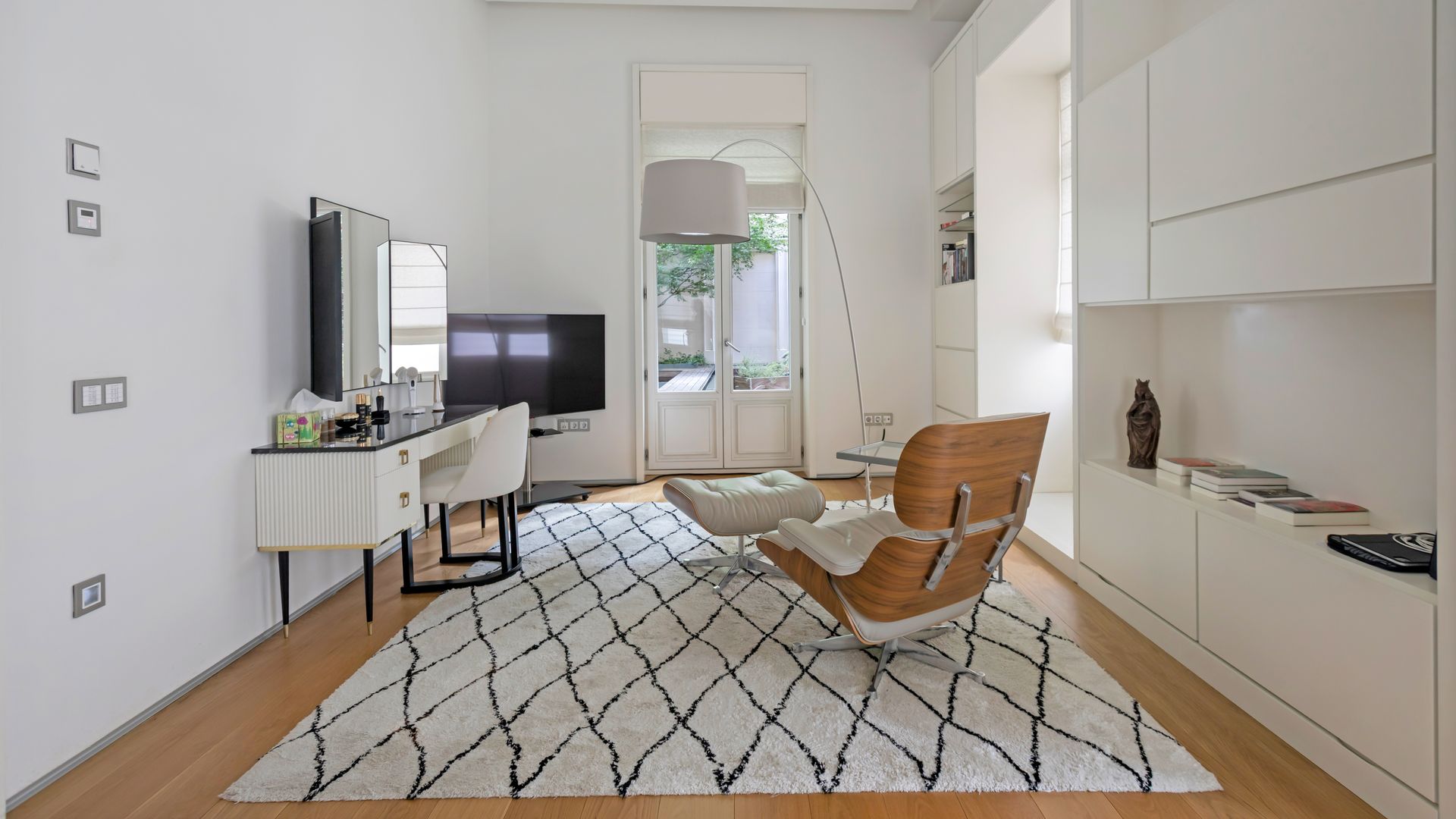 Dormitorio con zona de tocador y rincón de lectura, alfombra, y la Eames Longue Chair