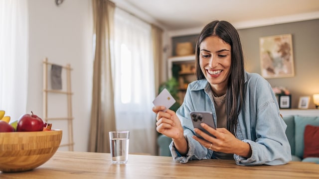 Una mujer comprando online con un móvil y una tarjeta de crédito