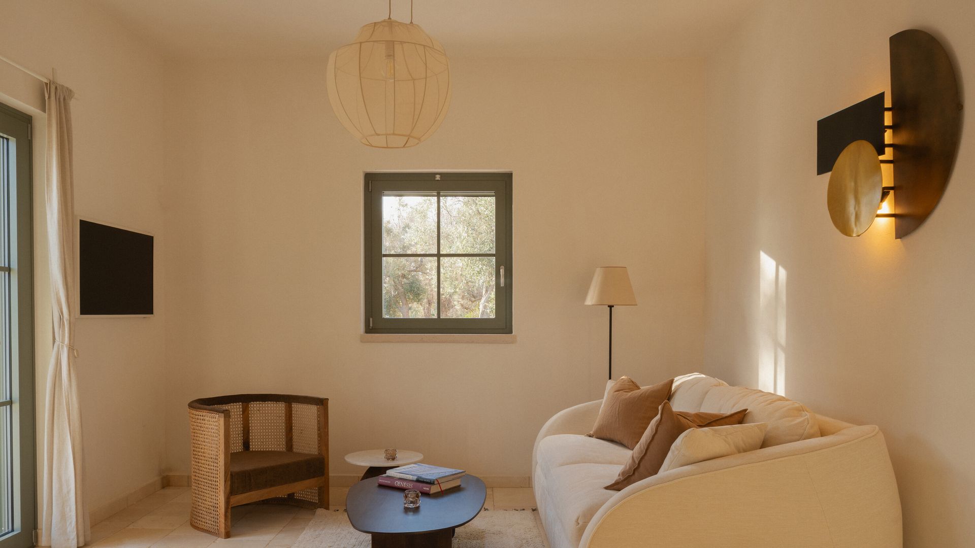 Salón minimalista en tonos neutros claros, sofá beige, suelo de madera, ventanas de madera verdes, lámpara de techo, aplique de pared, lámpara de pie