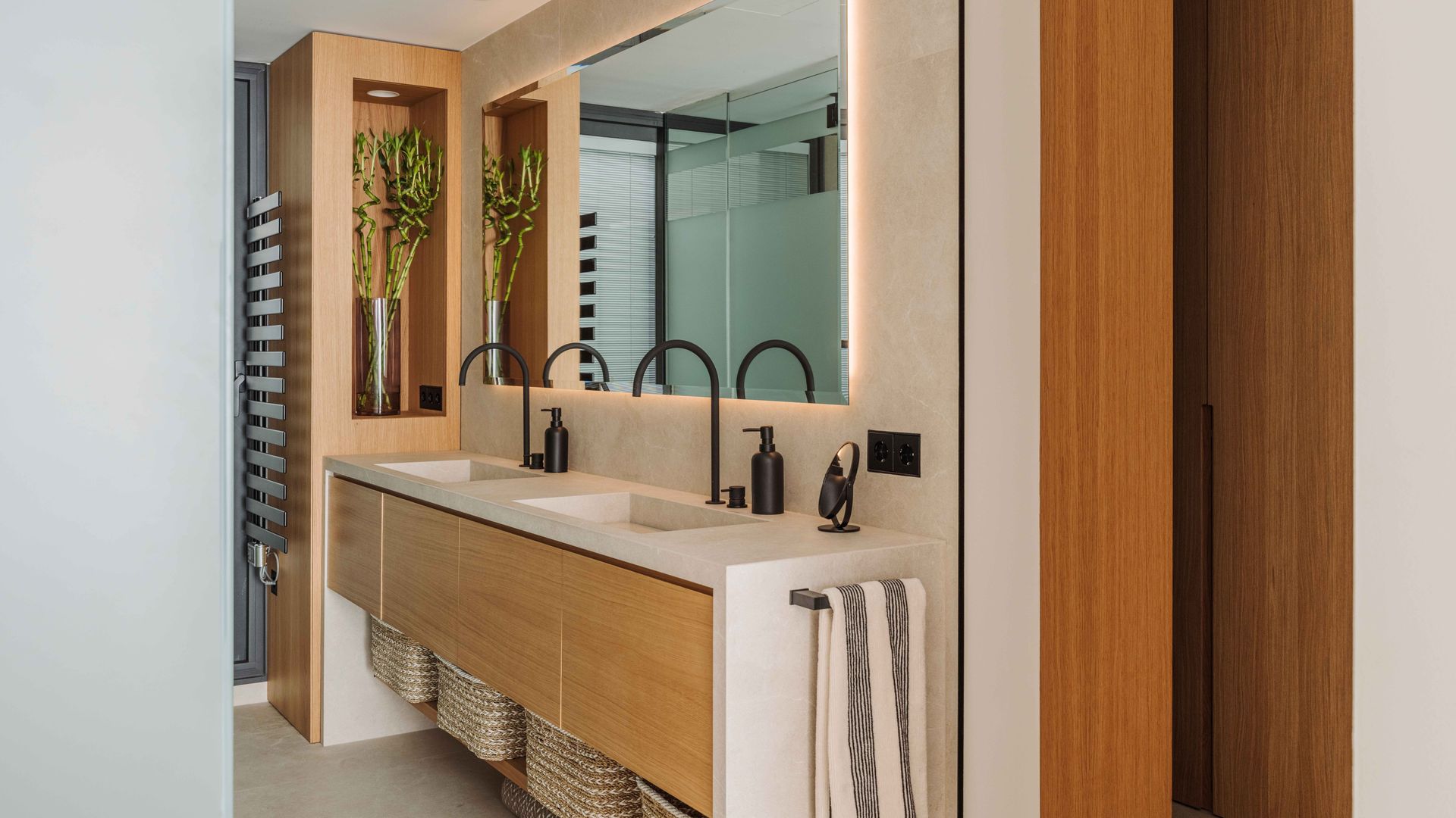 Baño con dos lavamos, grifería negra. hornacina, espejo retroiluminado, mueble volado, cestas bajo el mueble, radiador toallero