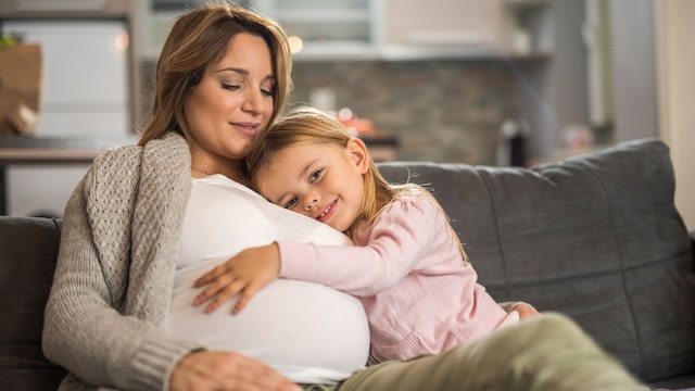 Niña abraza feliz la tripa de su madre, embarazada