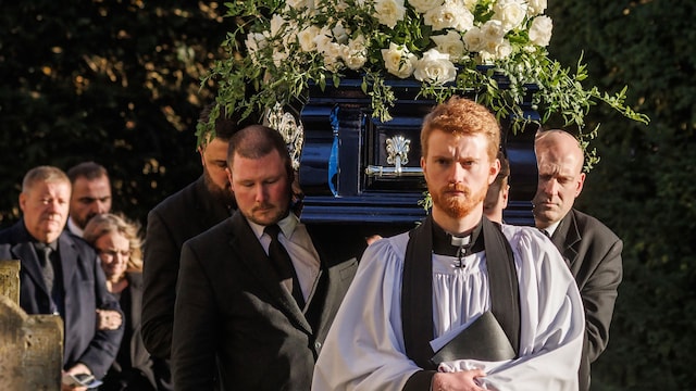 Plano medio del sacerdote marchando con el ataúd de Liam Payne