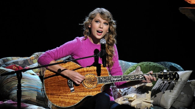 Plano medio de Taylor Swift tocando la guitarra en el CMA Music Awards