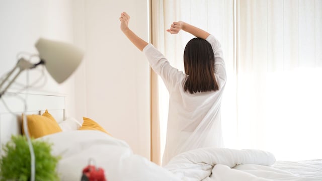 Una mujer estirándose en su cama