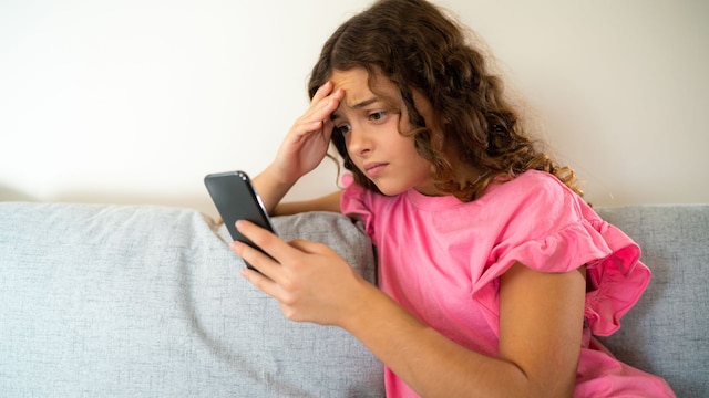Niña mira el móvil con preocupación