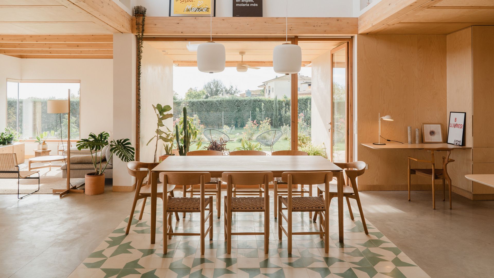 Comedor con gran ventanal de madera, mesa de madera, despacho en un lateral, revestimiento madera clara, mesa de comedor, alfombra 