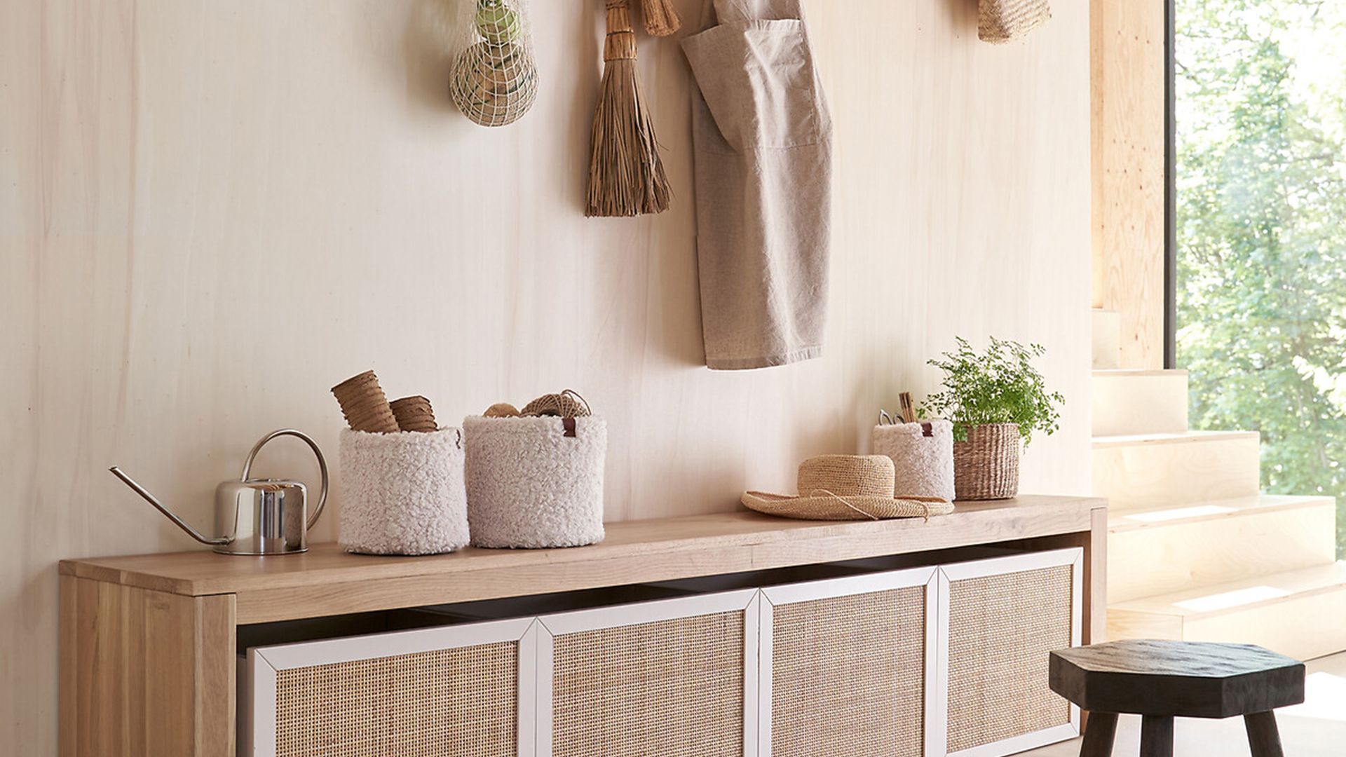 Recibidor con banco con cajones de rafia, perchero de pared de madera, taburete, cestas, plantas