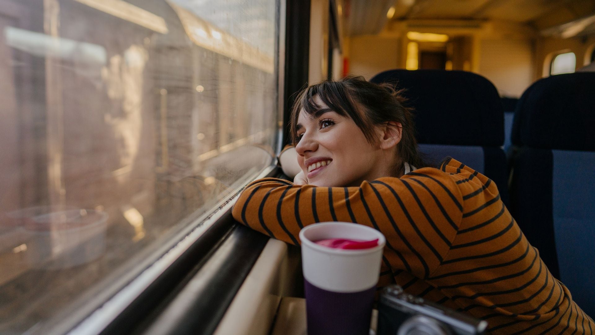Mujer feliz mirando por la ventana mientras viaja en tren