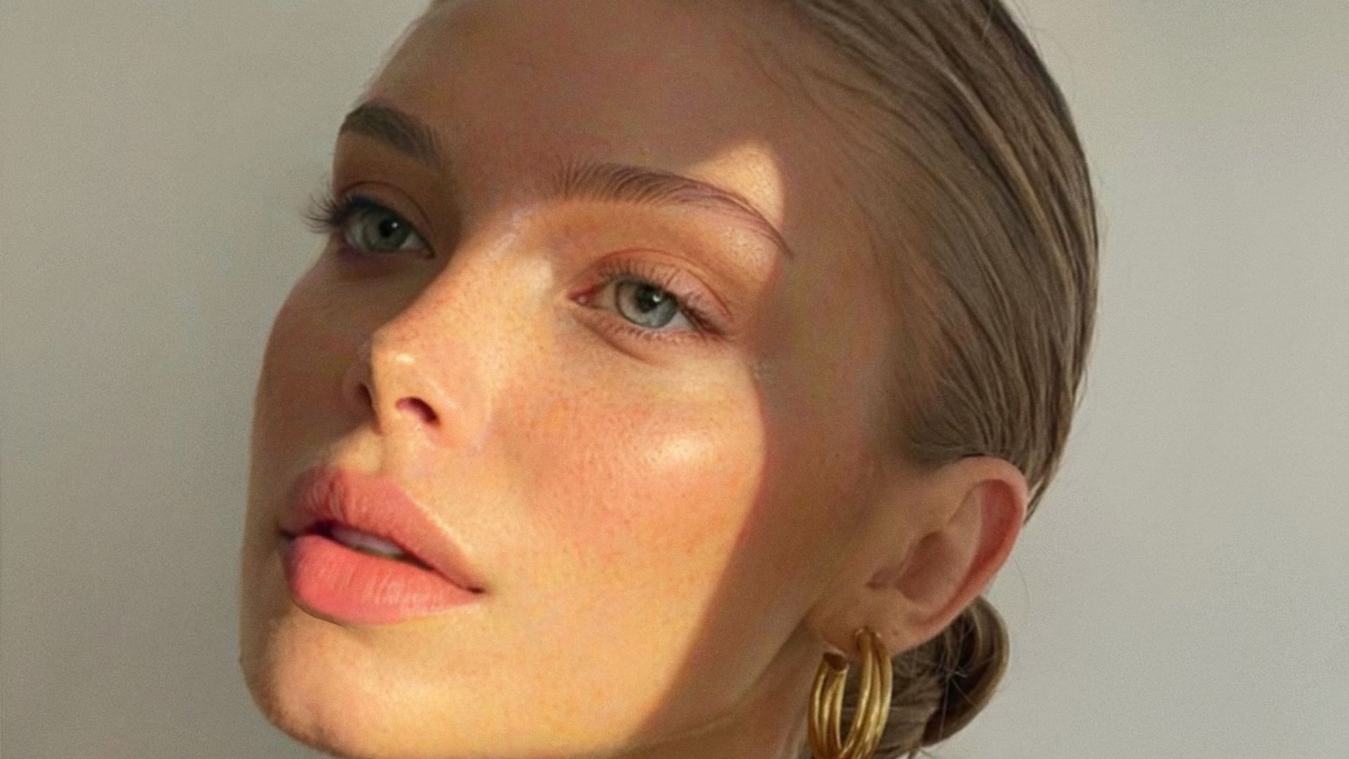 Primer plano mujer rubia con piel luminosa y joyas doradas