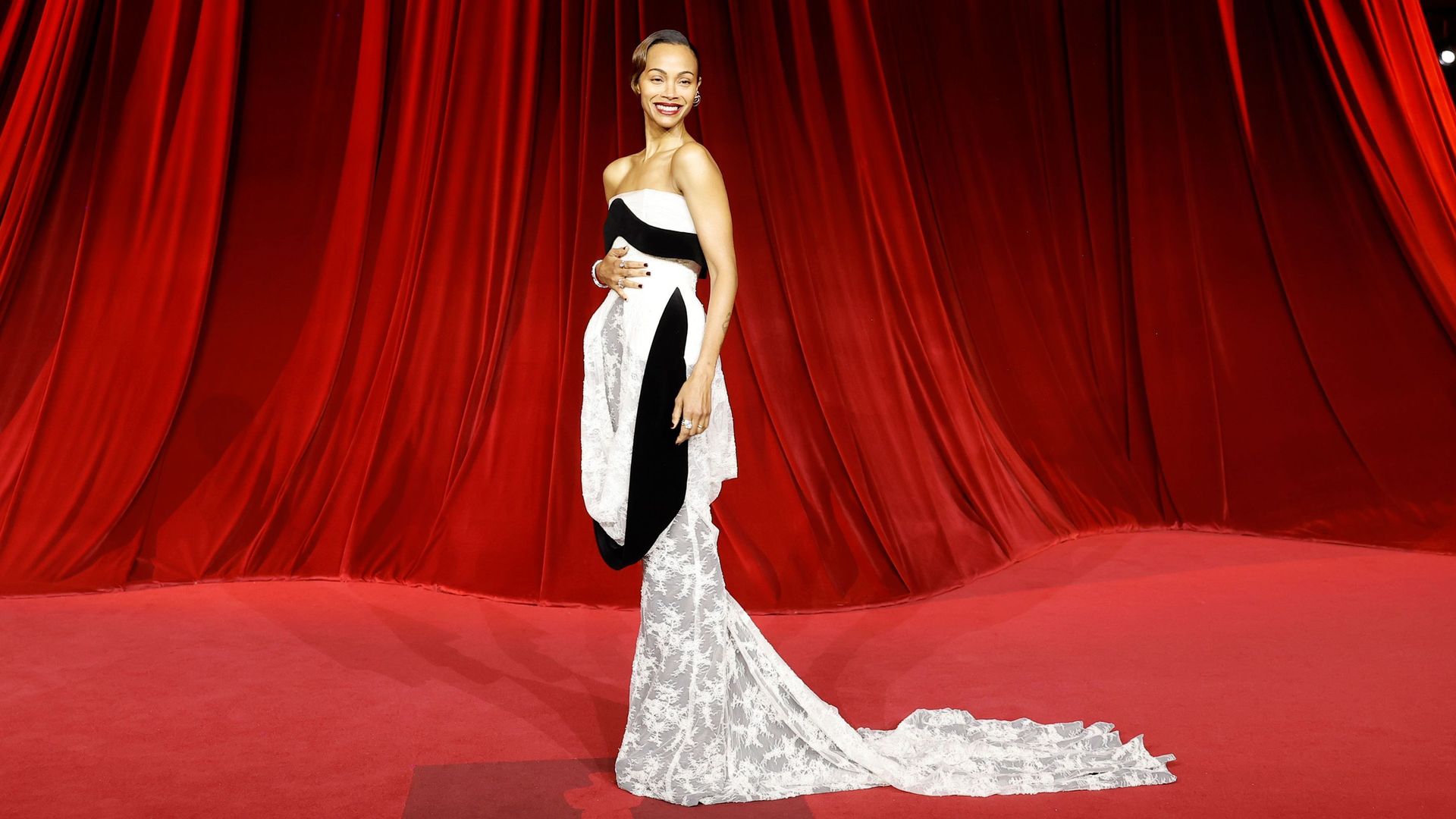 Plano entero de Zoe Saldaña en la Academy Museum Gala con vestido blanco con cola