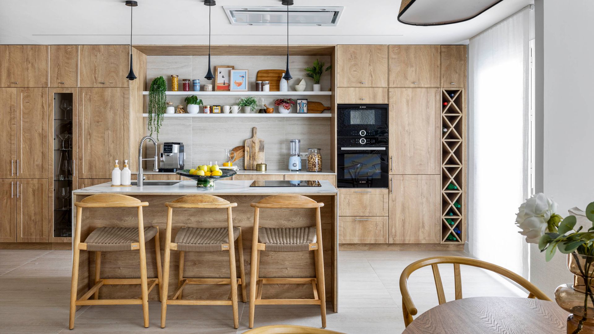 Cocina abierta con suelo de madera, muebles de madera, isla, electrodomésticos integrados, campana de techo