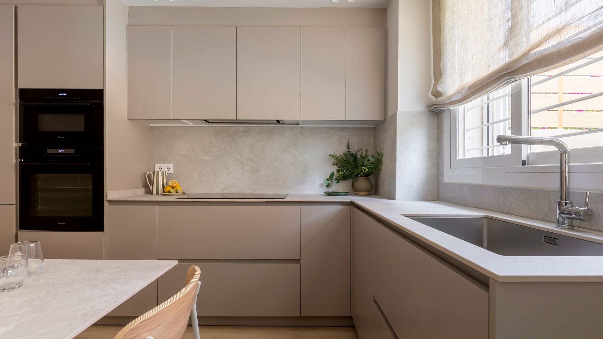 Cocina beige con horno y microondas en columna, estores, comedor en una esquina