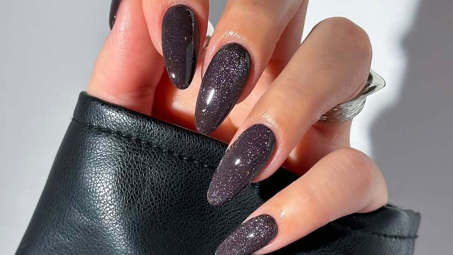 Manicura cat eye en negro con partículas brillantes y acabado glossy.