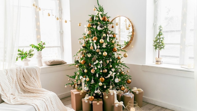 Decoración de Navidad de un salón en blanco, dorado y marrón con regalos bajo el árbol. Decoración Escandinava.