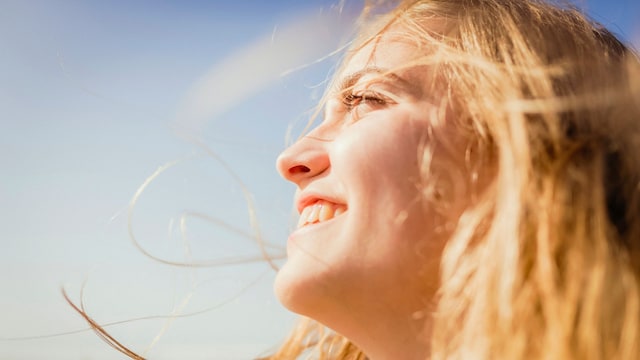 Mujer sonriendo con el sol en la cara en primer plano