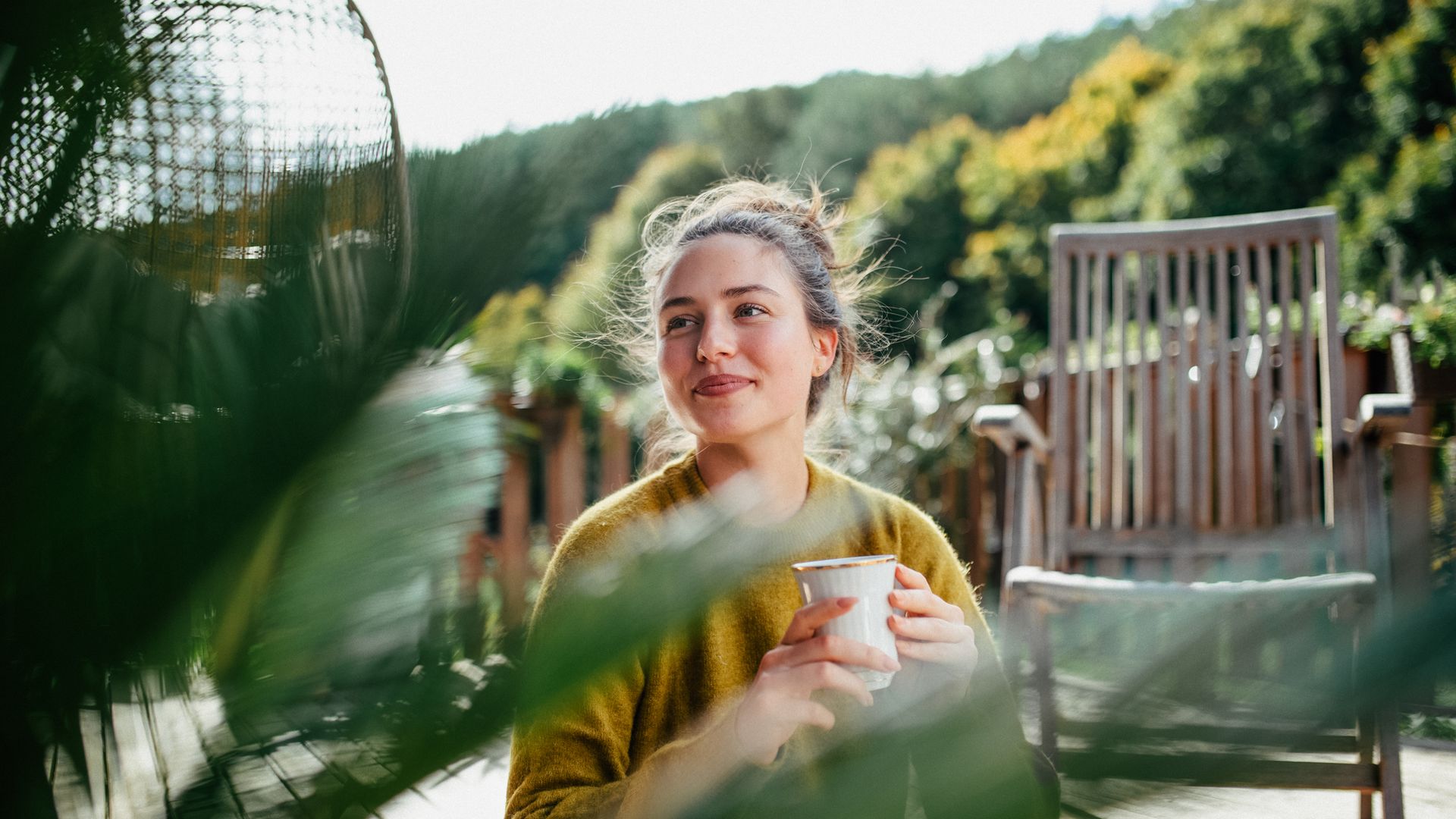 Mujer disfrutando, en su patio, de una taza de café matutina.