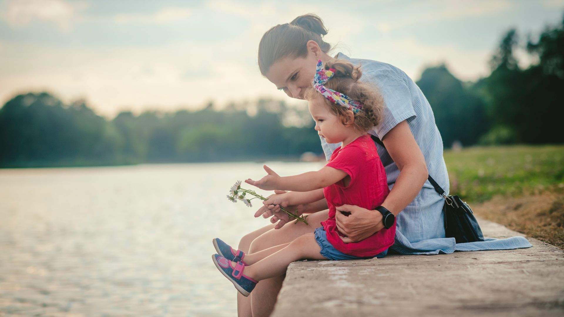 madre e hija sentadas junto a un lago