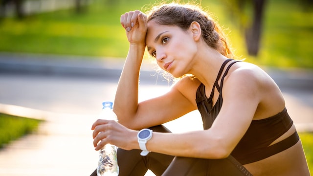 Mujer con ropa de deporte cansada y bebiendo agua