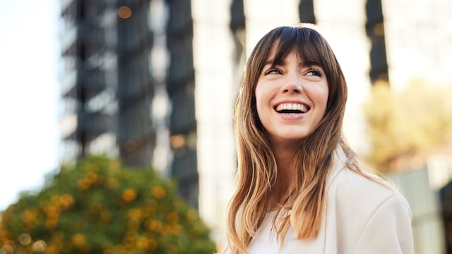Mujer joven sonriendo en la calle con una chaqueta