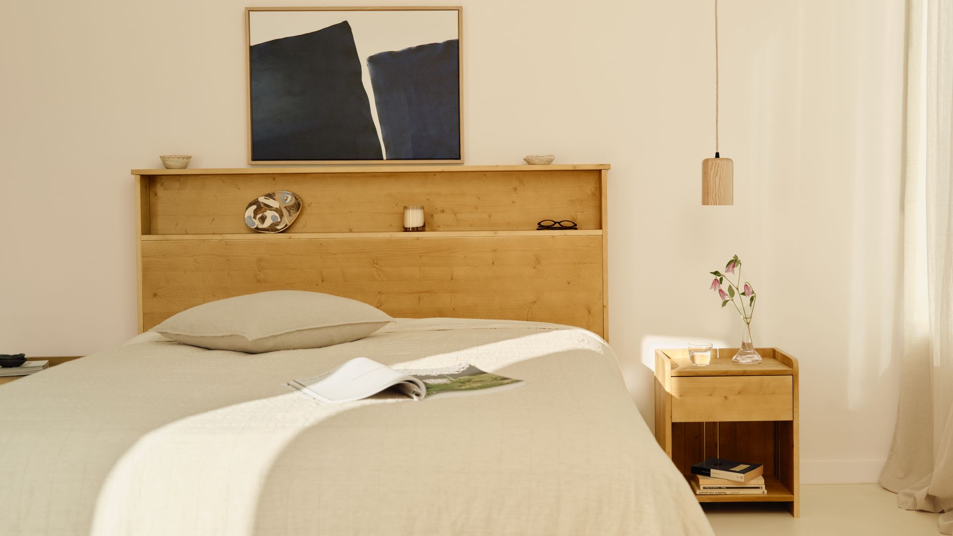 Dormitorio con cabecero de madera con repisa, cuadro sobre la repisa, mesita de noche de madera, ropa de cama blanca 