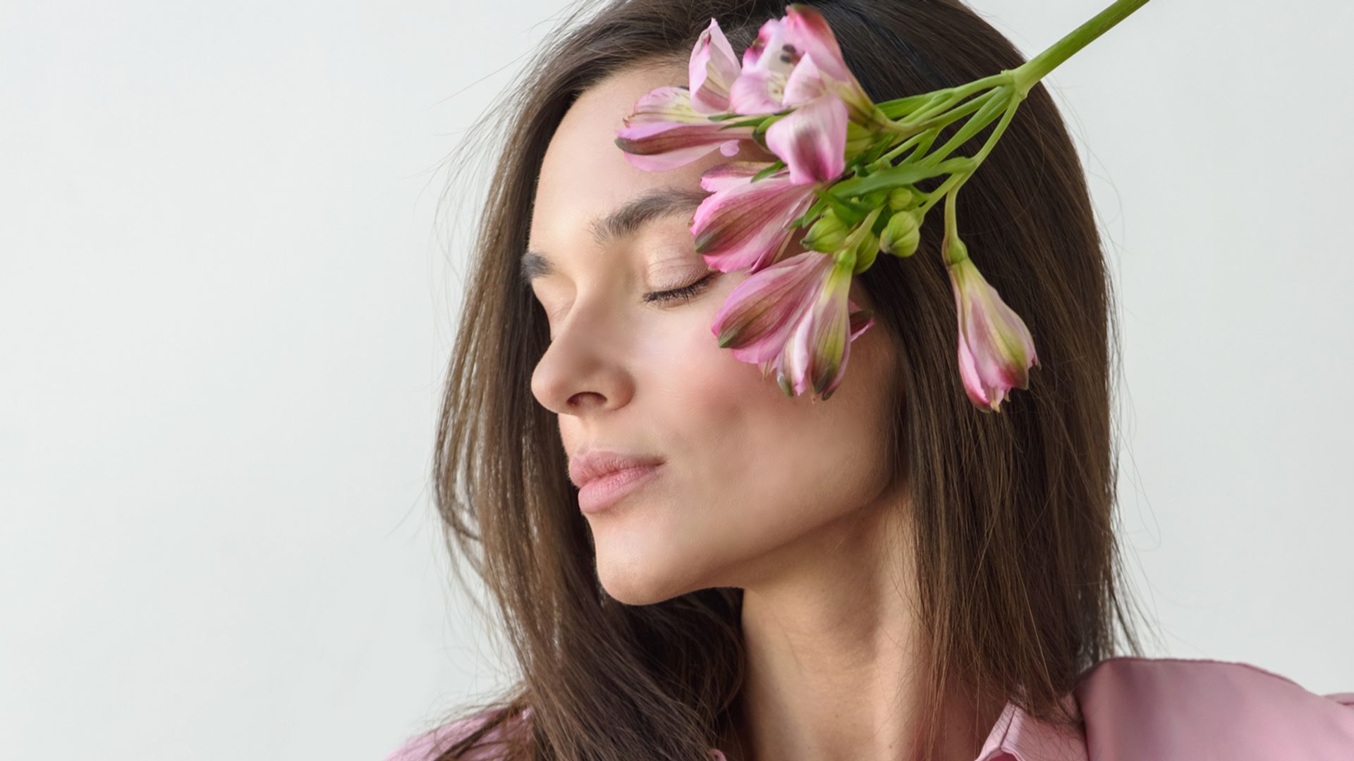 Rostro de mujer con piel clara y rostro ladeado, con una flor sobre la mejilla