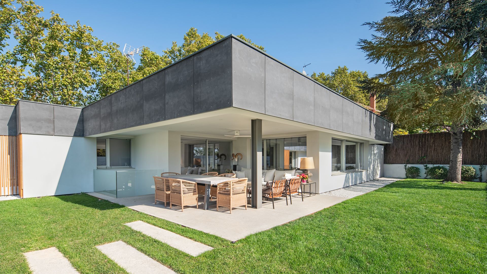 Porche con comedor y zona de estar con sillas de fibras vegetales