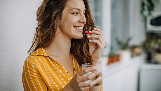Mujer tomando suplemento de hierro con un vaso de agua