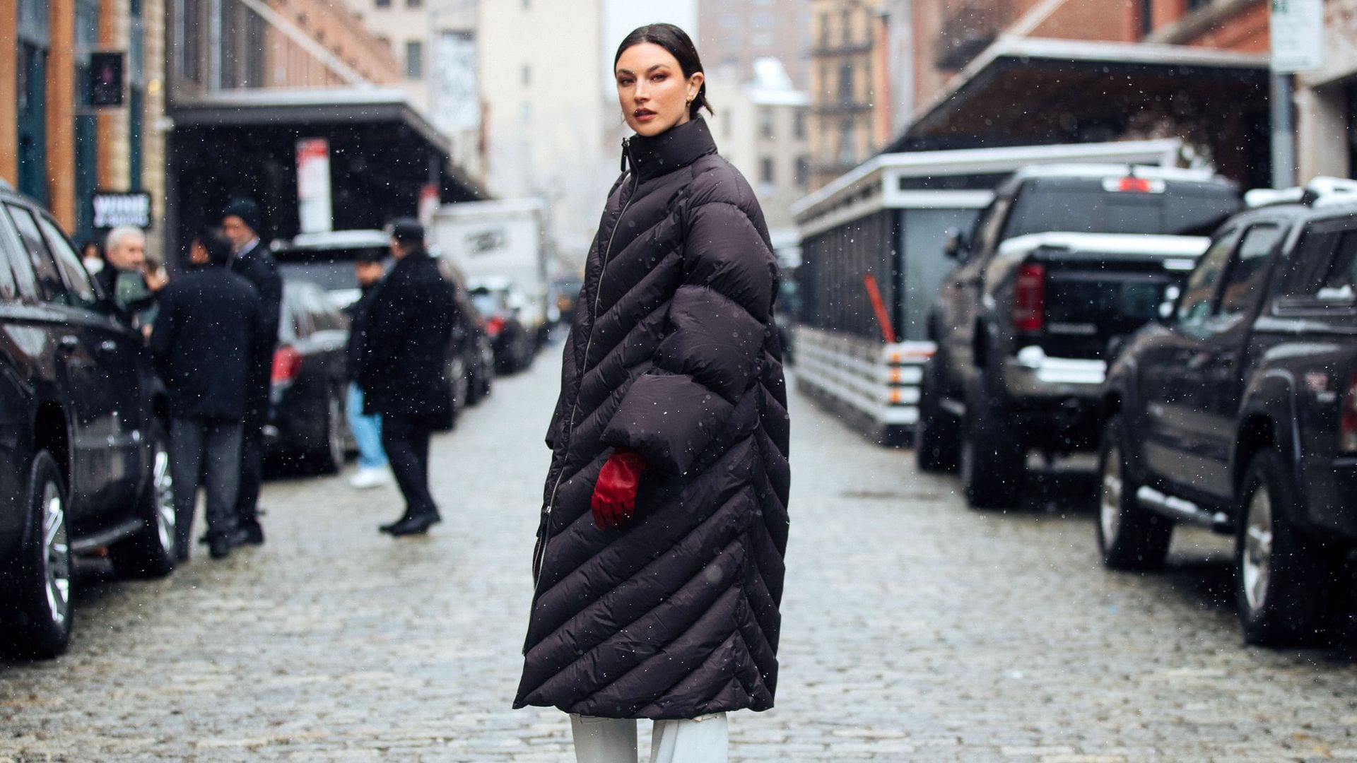 Jacquelyn Jablonski con abrigo largo acolchado, botas blancas y guantes rojos en New York Fashion Week