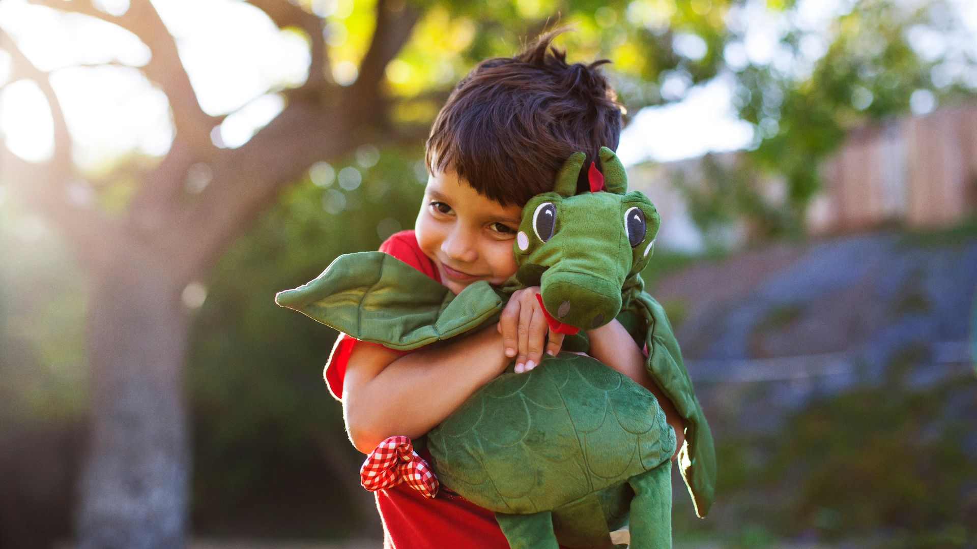 Niño abrazando a un dragón de peluche