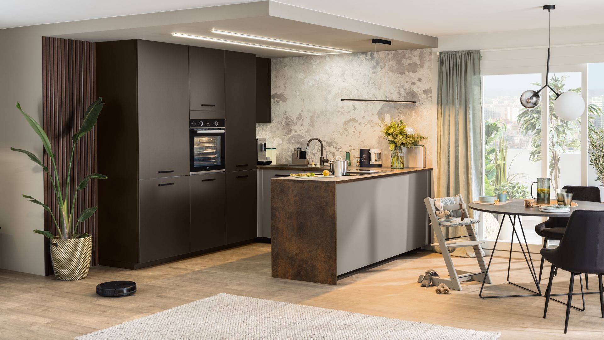 Cocina abierta con península y muebles de color marrón oscuro y claro, alfombra y suelo de madera 