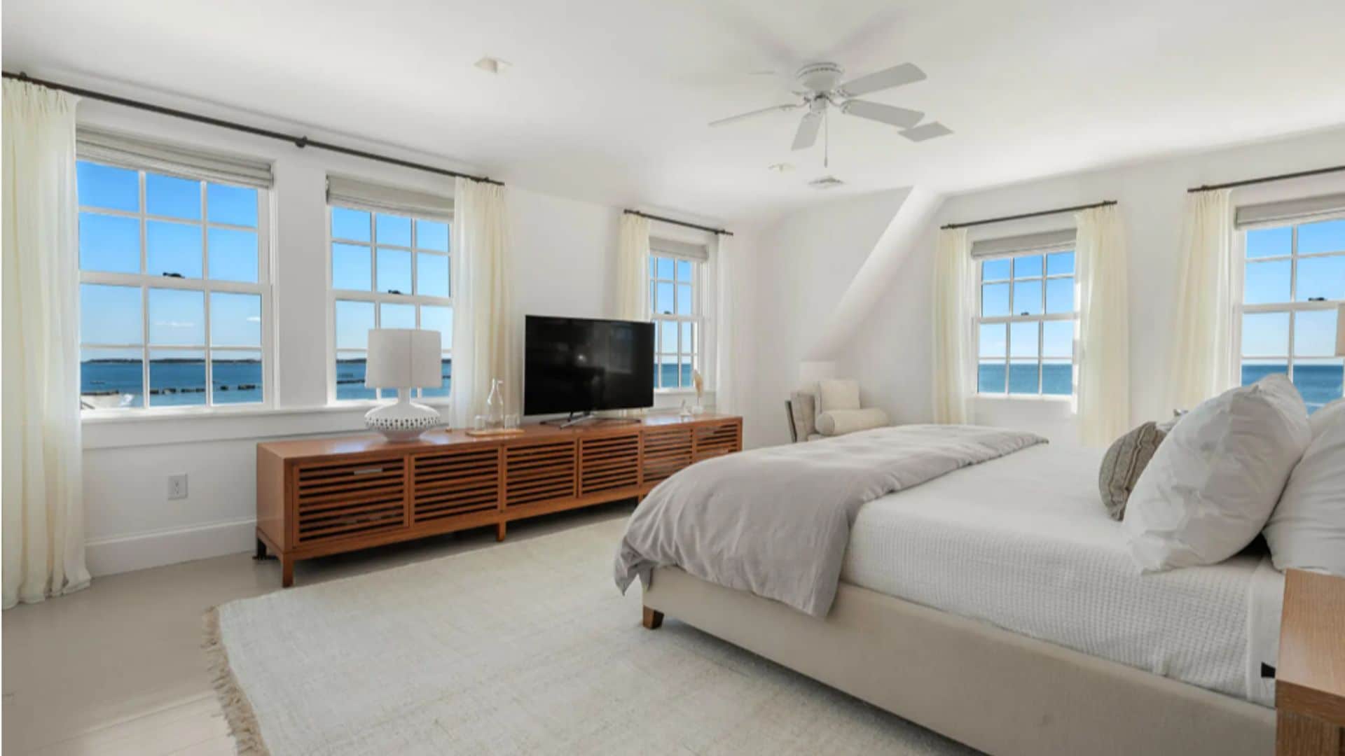 Mansión Taylor Swift, dormitorio principal con ventilador de techo, alfombra, cortinas blancas, mueble de televisión de madera y cama tapizada