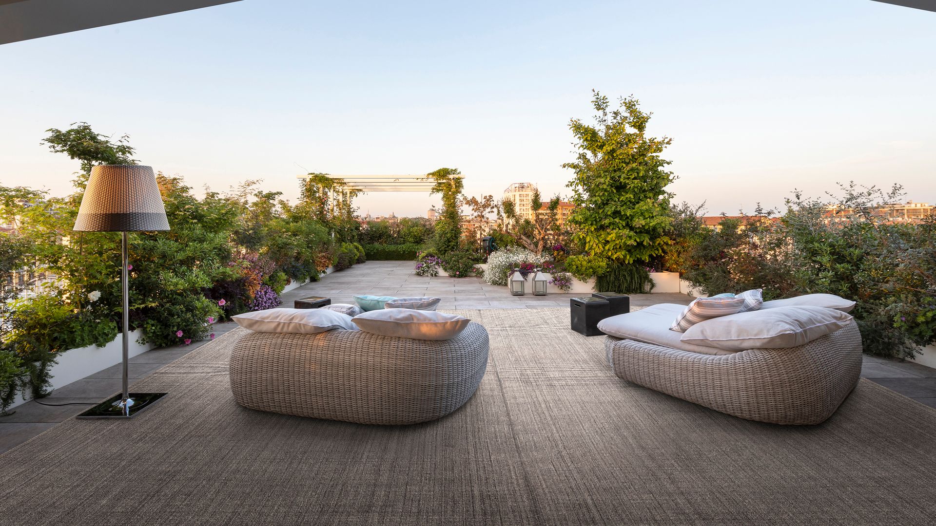 Terraza con alfombra de fibras vegetales, puffs, plantas y lámpara de pie