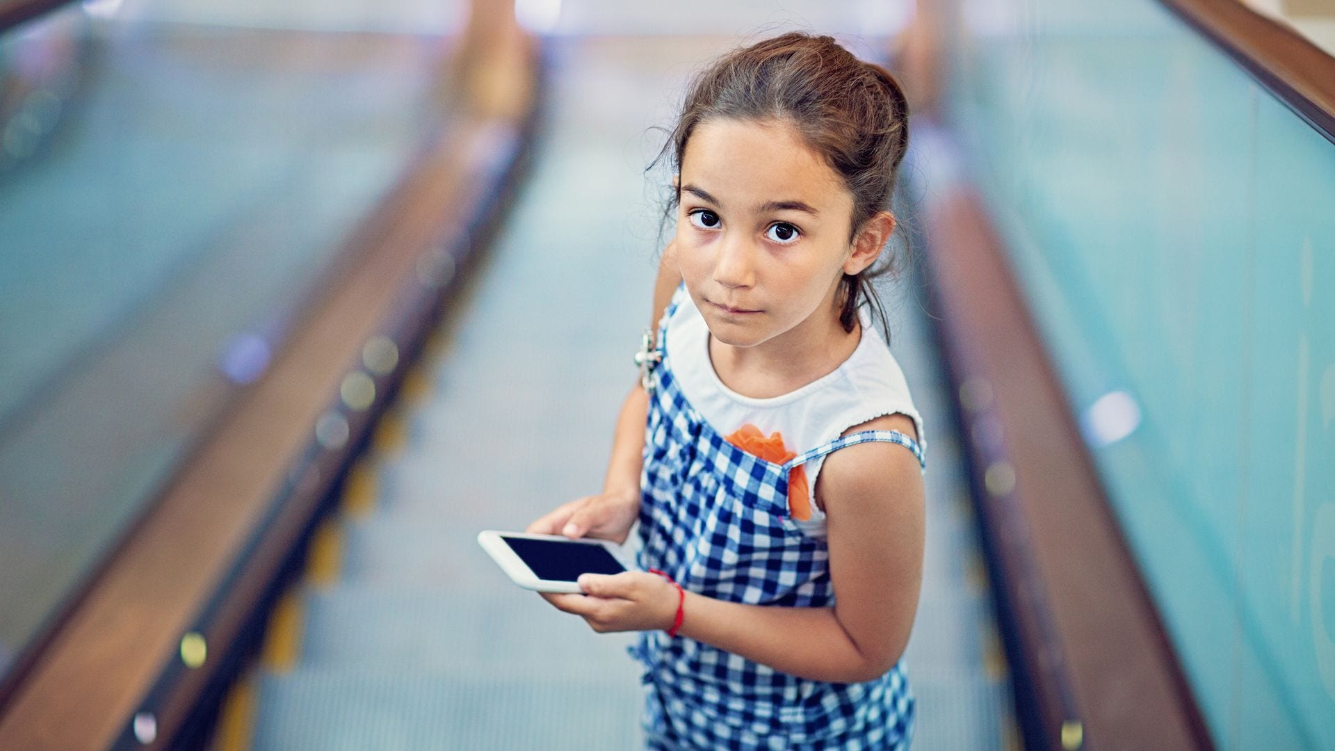 Niña seria con el móvil en la mano