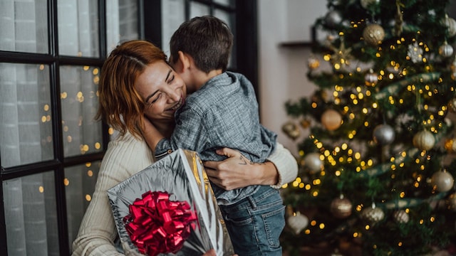 Madre abrazando a su hijo al recibir un regalo de Navidad