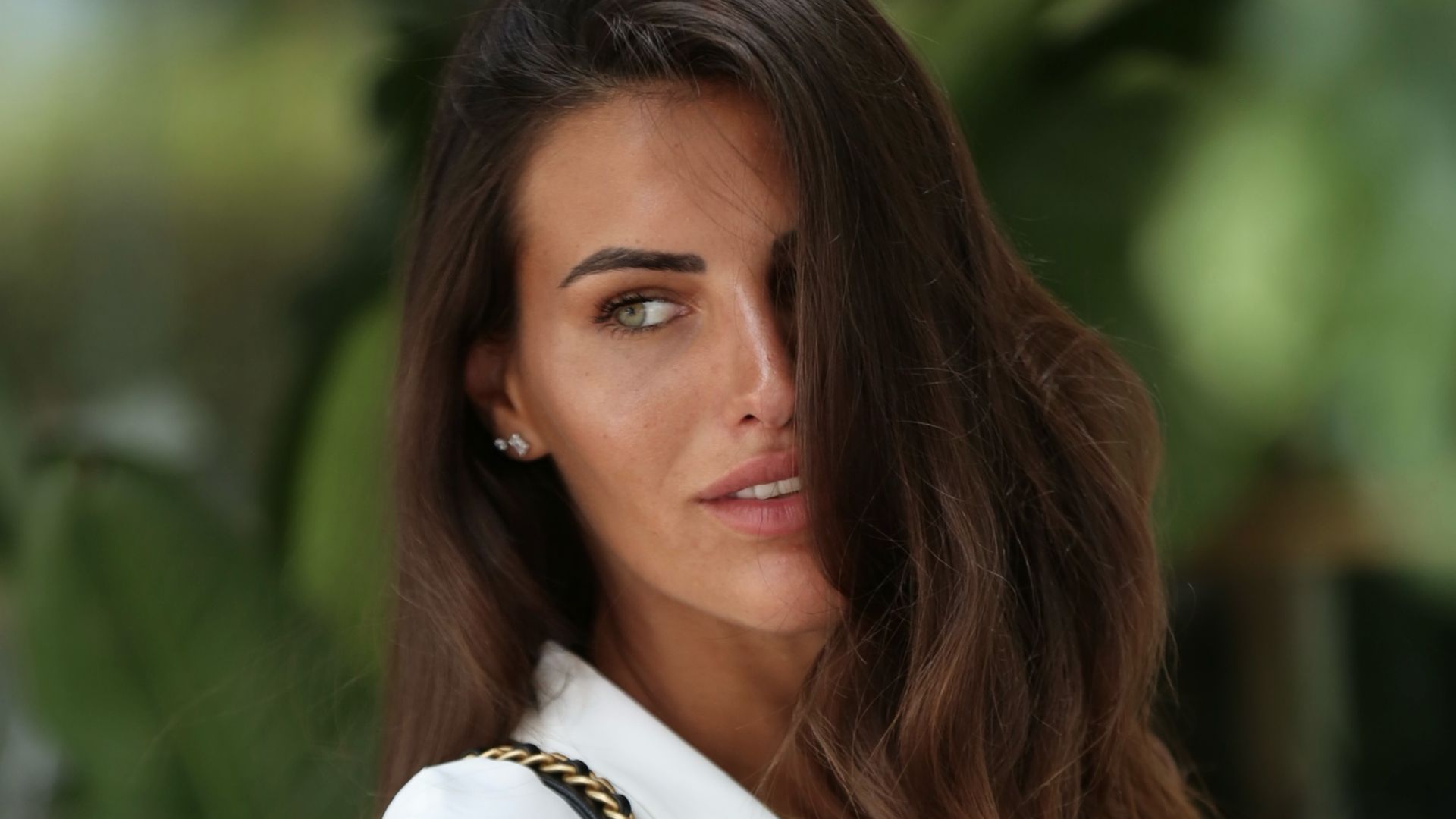 Carolina Stramare con pelo suelto, camisa blanca, bolso de cadena y pelo suelto por un lado de la cara