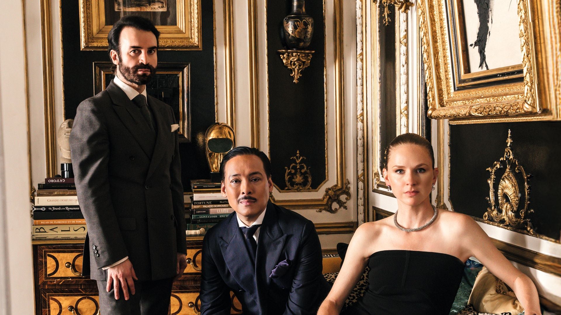Michael y Jean-Pierre, junto a su amiga Anna Philippa Wolf, en el salón dorado de la casa. Un espacio enmarcado por molduras y "boiseries" doradas y paneles lacados en negro, en donde destaca un cuadro pintado por el propio Michael Coorengel; un banco estilo Imperio que proviene del castillo familiar de Jean-Pierre, donde están sentados, y la cómoda de estilo siglo XVII, de Maison Jansen