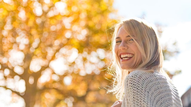 mujer sonr e bajo el sol en invierno
