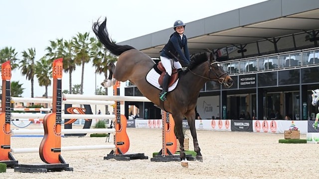 Plano medio de Emma Behn saltando con su caballo en una competición