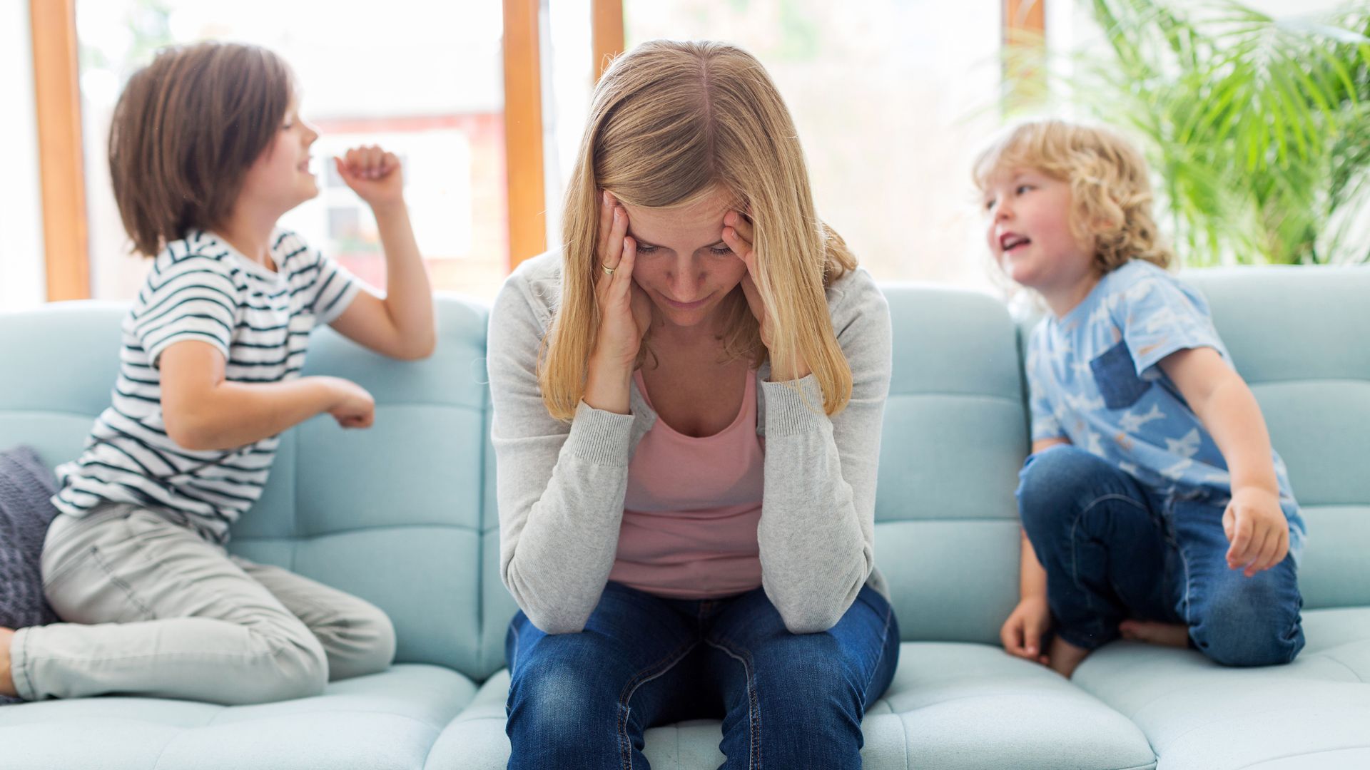 Madre en actitud ansiosa y agotada con sus dos hijos