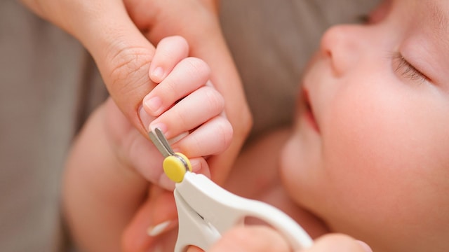 Madre cortando uñas a un bebé