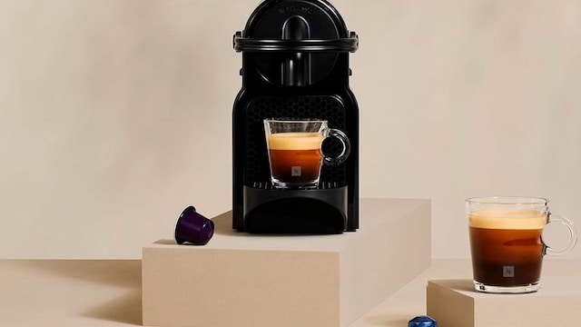 Una cafetera Nesspreso junto a cápsulas en un expositor