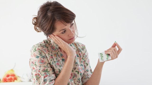 mujer deprimida con unas pastillas en la mano